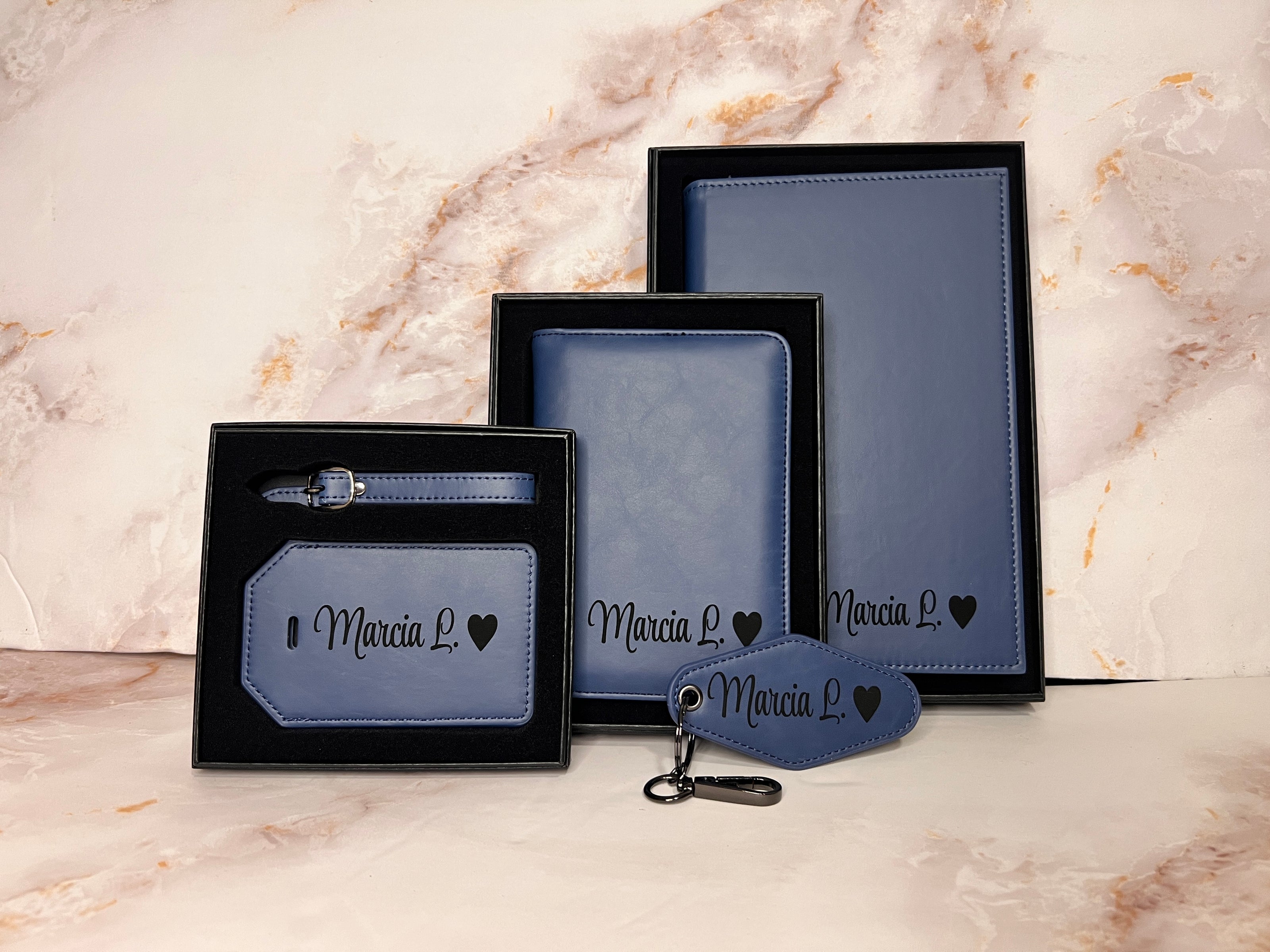 Set of personalized leather items with 'Marcia L.' engraving on a marble background